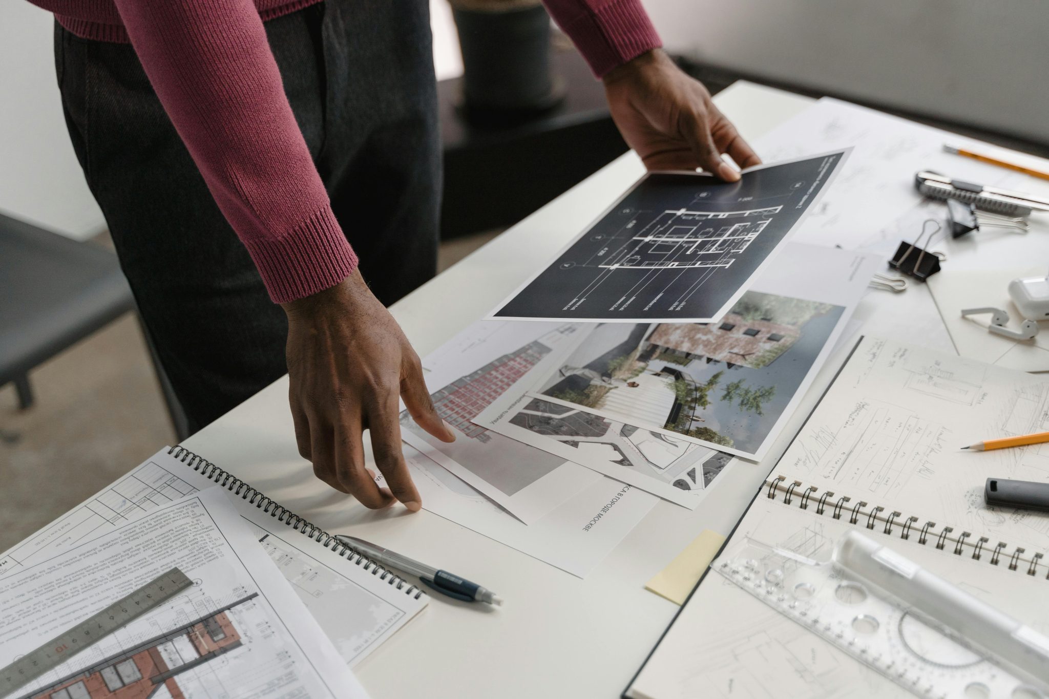 Architect evaluates blueprints on a desk, showcasing modern workspace creativity and design.